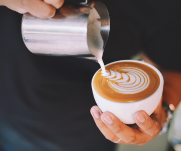 Barista making a design on fresh cappucino