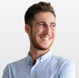 A smiling man with arms crossed looking at the distance